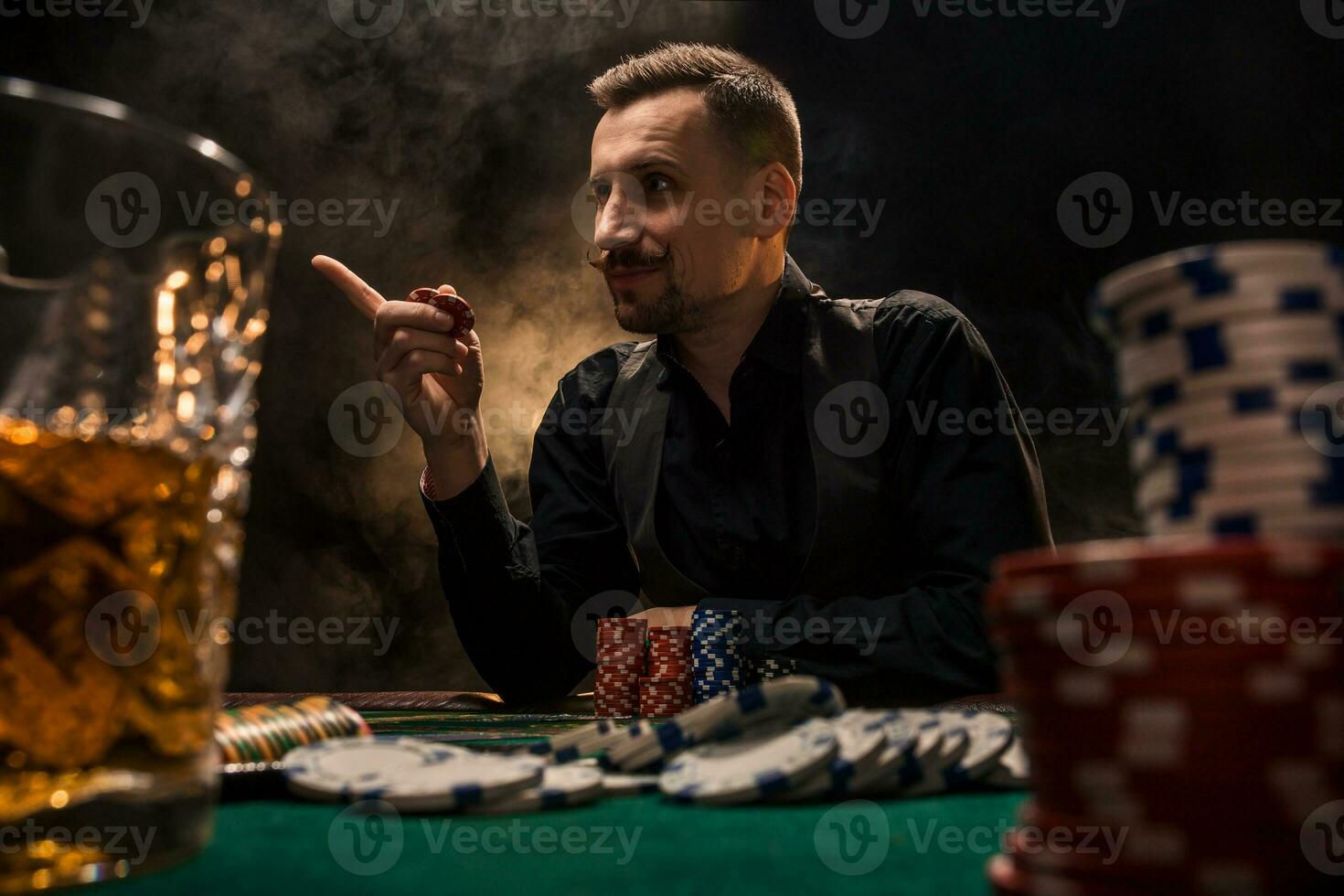 Man is playing poker with a cigar and a whiskey. A man winning all the chips on the table with thick cigarette smoke. photo