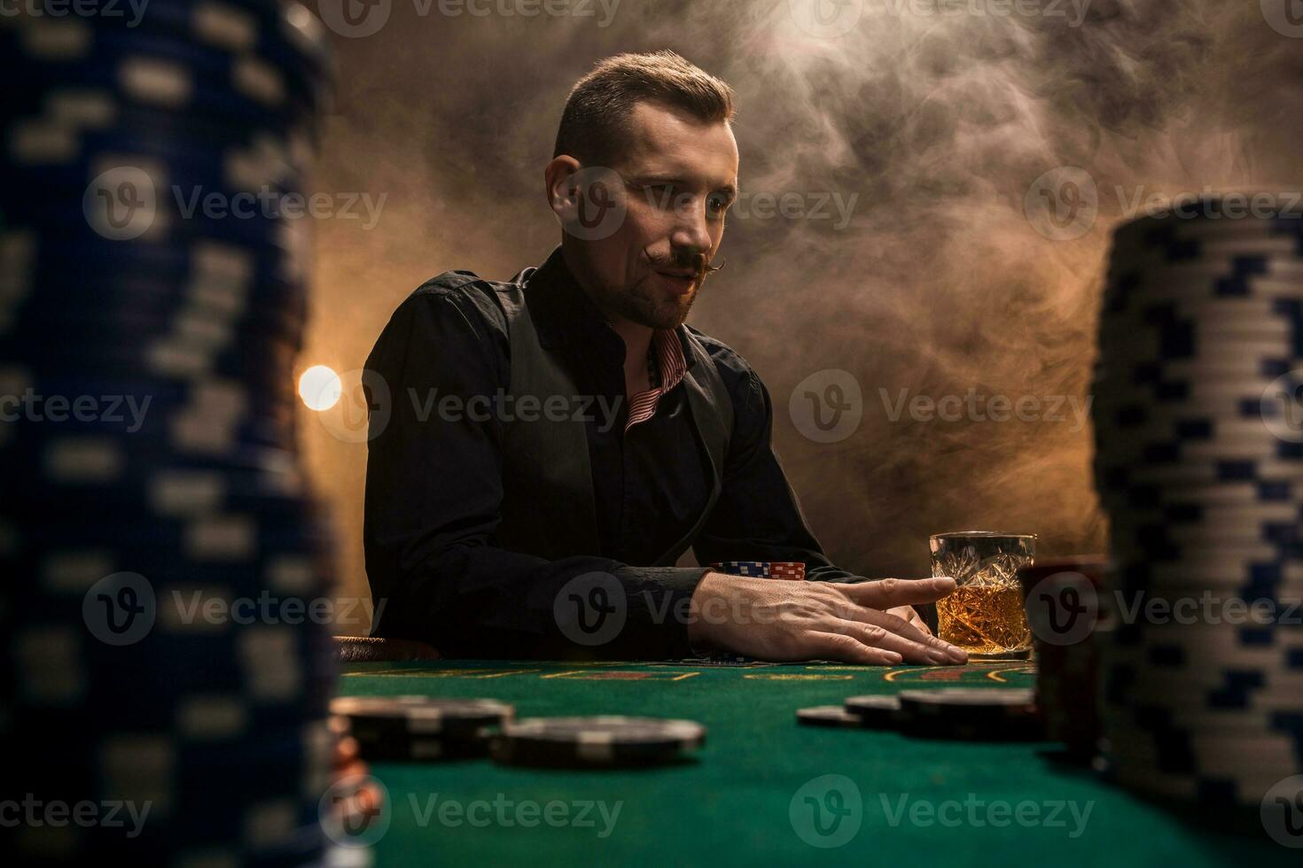 Young handsome man sitting behind poker table with cards and chips photo
