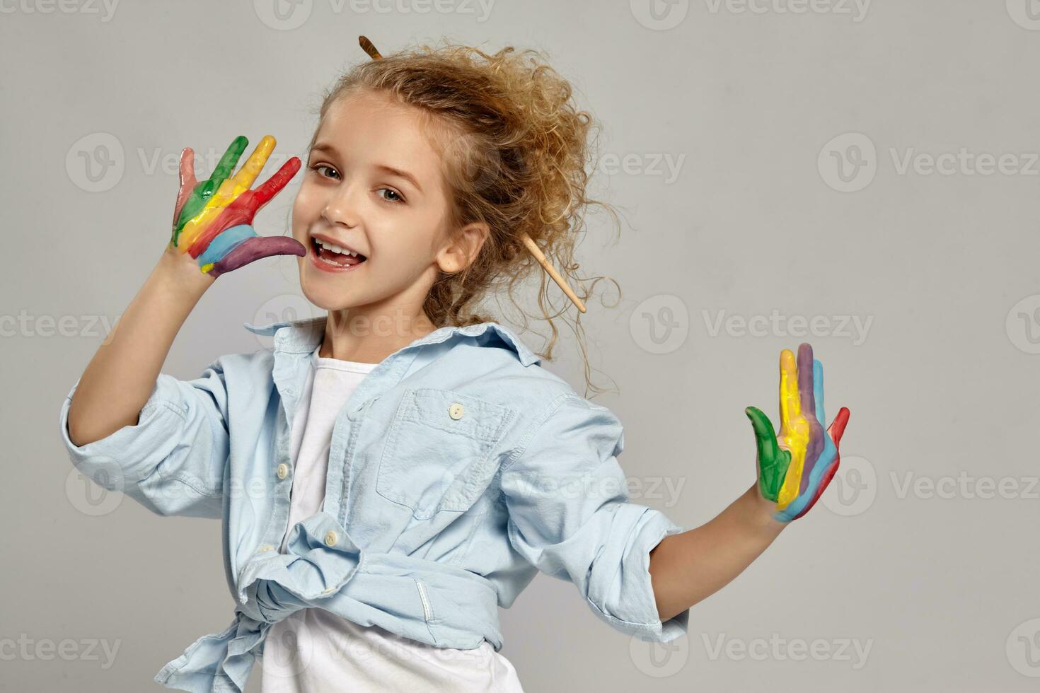 Beautiful little girl with a painted hands is posing on a gray background. photo