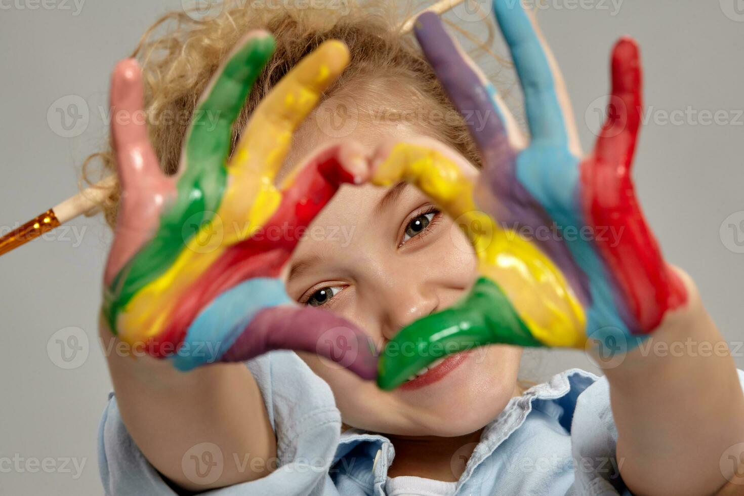 Beautiful little girl with a painted hands is posing on a gray background. photo