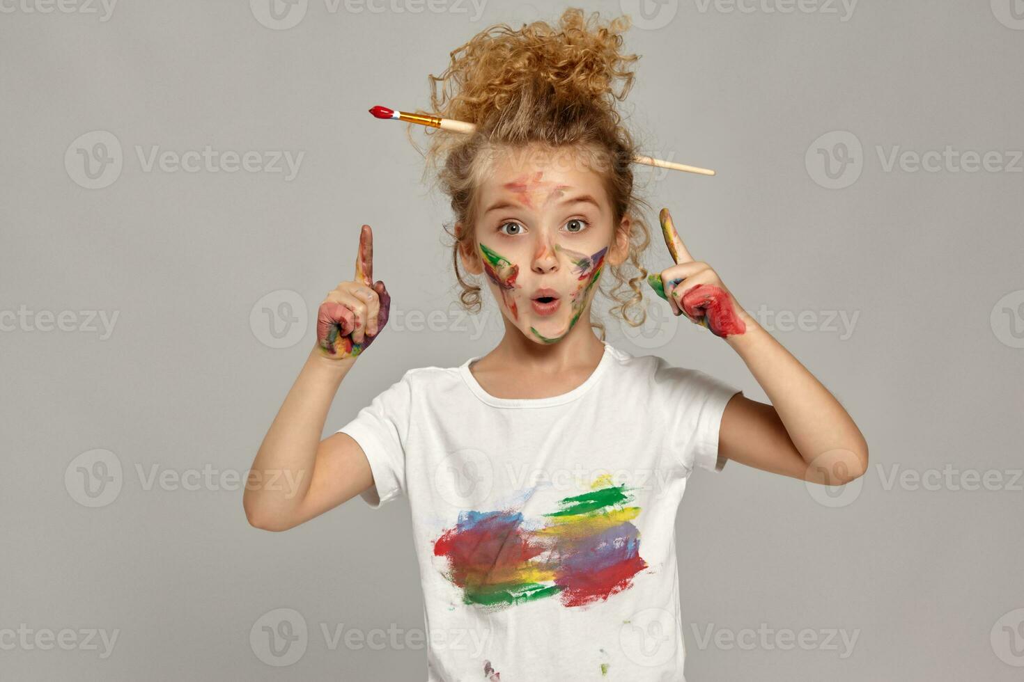 Beautiful little girl with a painted fingers is posing on a gray background. photo