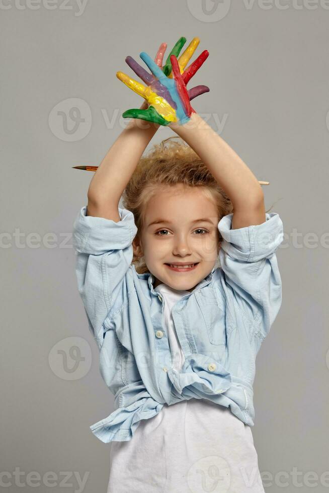 Beautiful little girl with a painted hands is posing on a gray background. photo