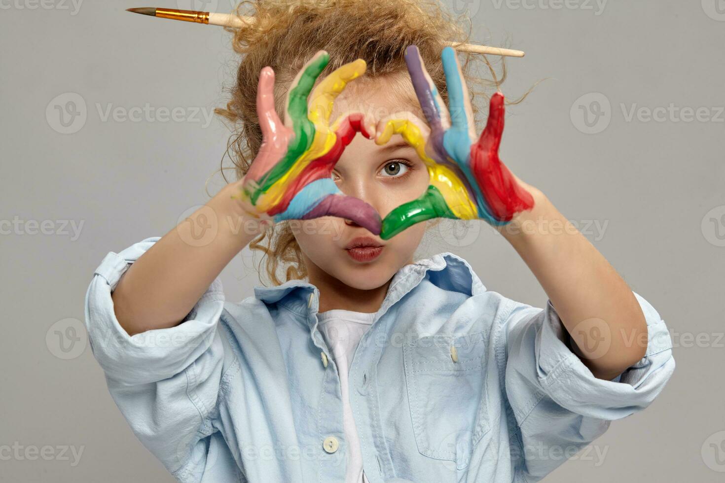 Beautiful little girl with a painted fingers is posing on a gray background. photo