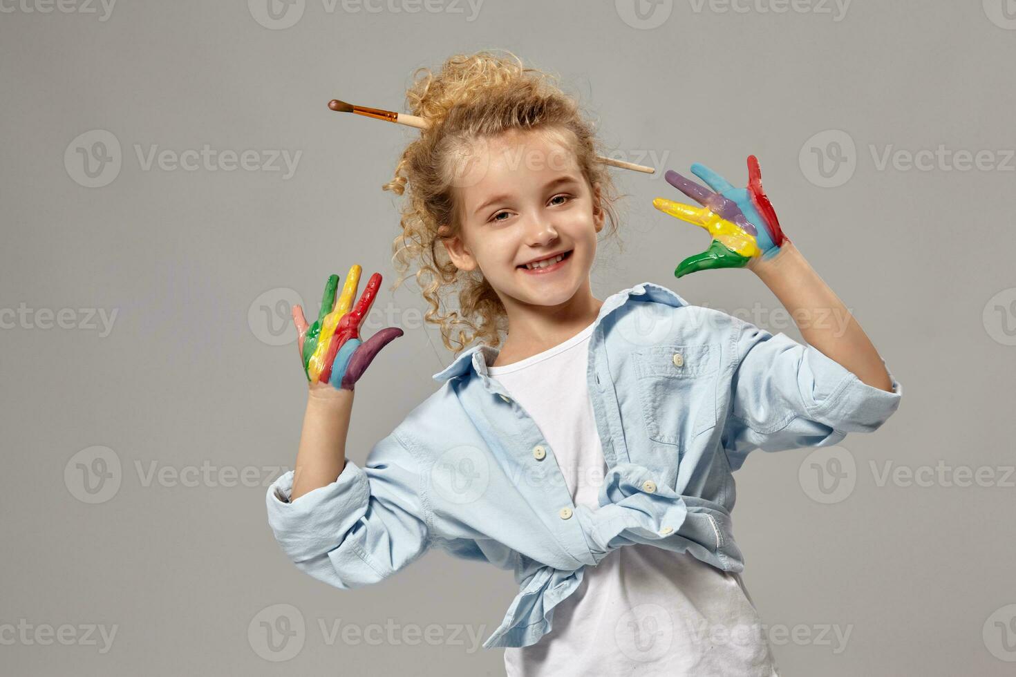 Beautiful little girl with a painted hands is posing on a gray background. photo