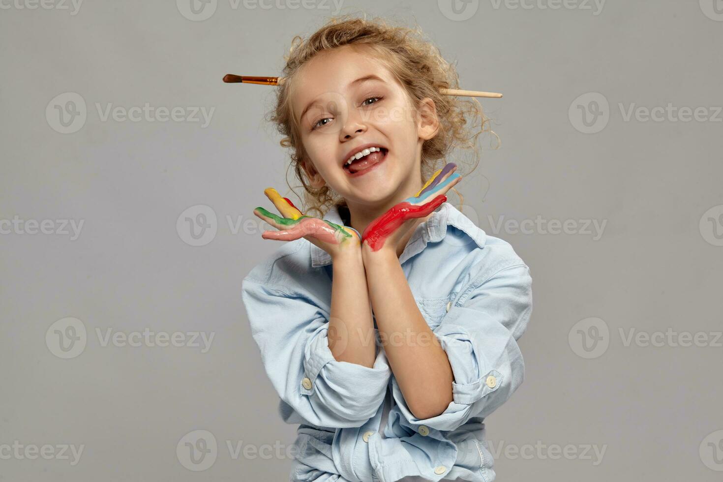 Beautiful little girl with a painted hands is posing on a gray background. photo