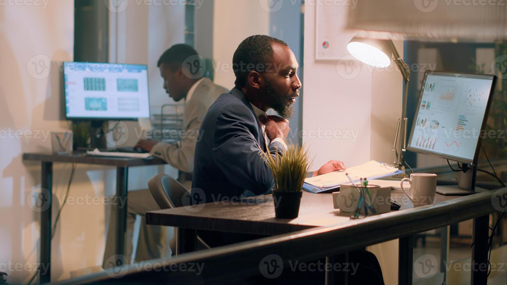 Manager checking online paperwork is in order during nightshift. Management executive looking over every office computer to verify employees managed to finish project tasks in time photo