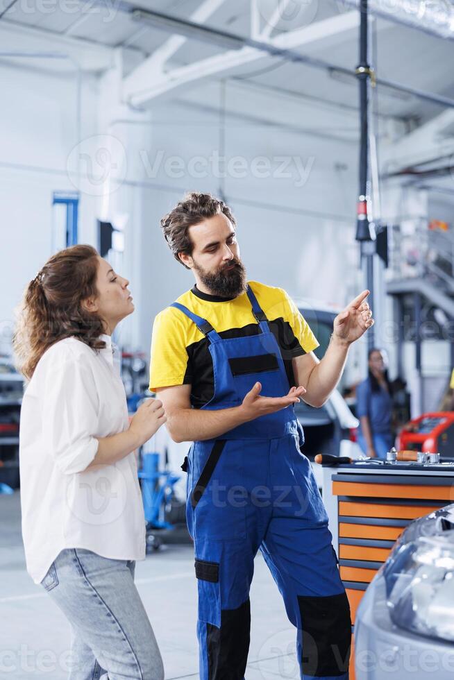 Expert in repair shop using AR technology to show customer car maintenance parameters. Garage worker using futuristic vr headset to inform client of what problems her vehicle is facing photo