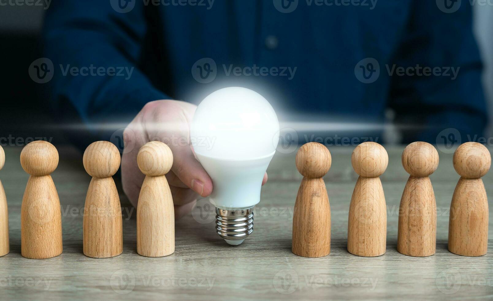 A man inserts a glowing light bulb idea between people. Inspire society to new ideas. Teamwork brainstorming. Research and development. Enlightenment and education. Ideology, paradigm photo