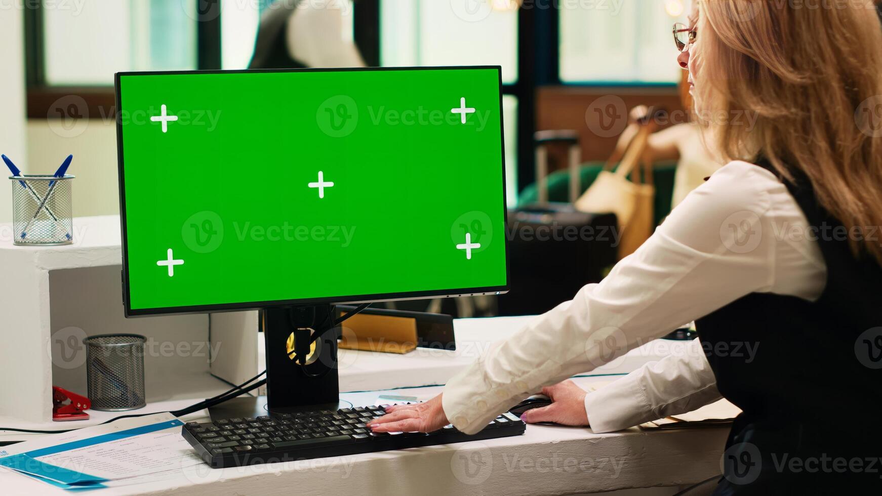 Front desk staff using greenscreen on pc in resort lobby, checking chroma key display with isolated template. Hotel receptionist looking at blank copyspace on computer. Tripod shot. photo