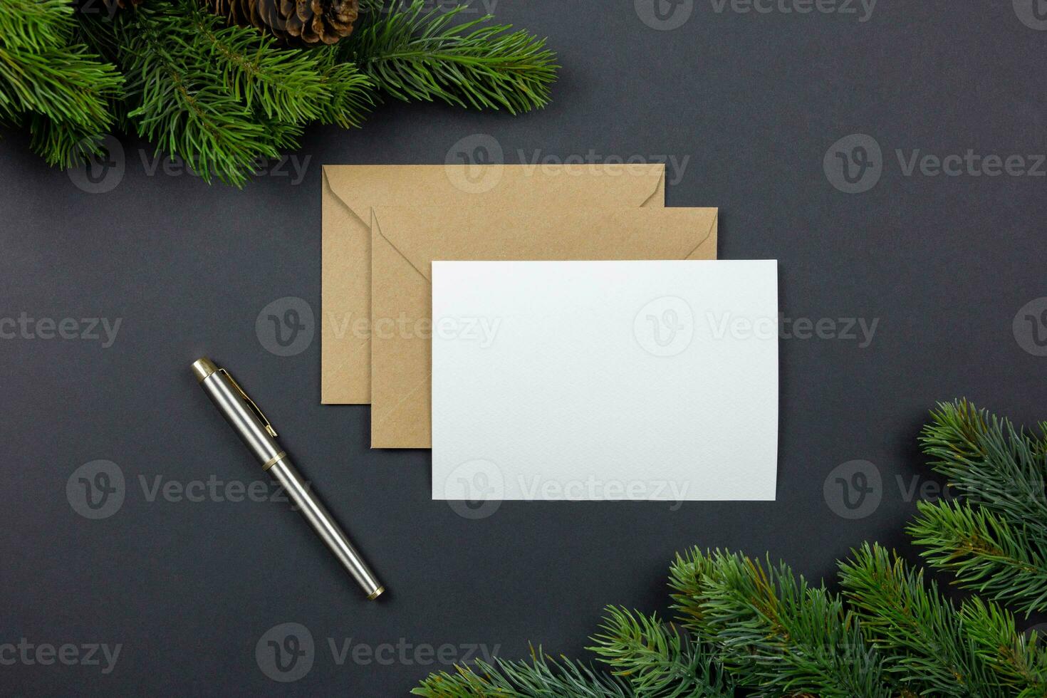 Christmas greeting card and envelope mockup with fir tree branches and decoration on dark background. Festive styled composition. Top view. photo