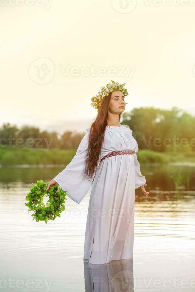 mujer en blanco vestir en el agua. Arte mujer con guirnalda en su cabeza en río. guirnalda en su cabeza, eslavo tradiciones y paganismo foto