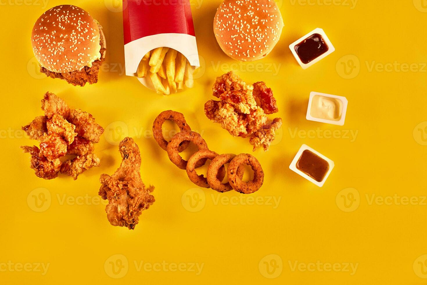 Top view hamburger, french fries and fried chicken on yellow background. Copy space for your text. photo