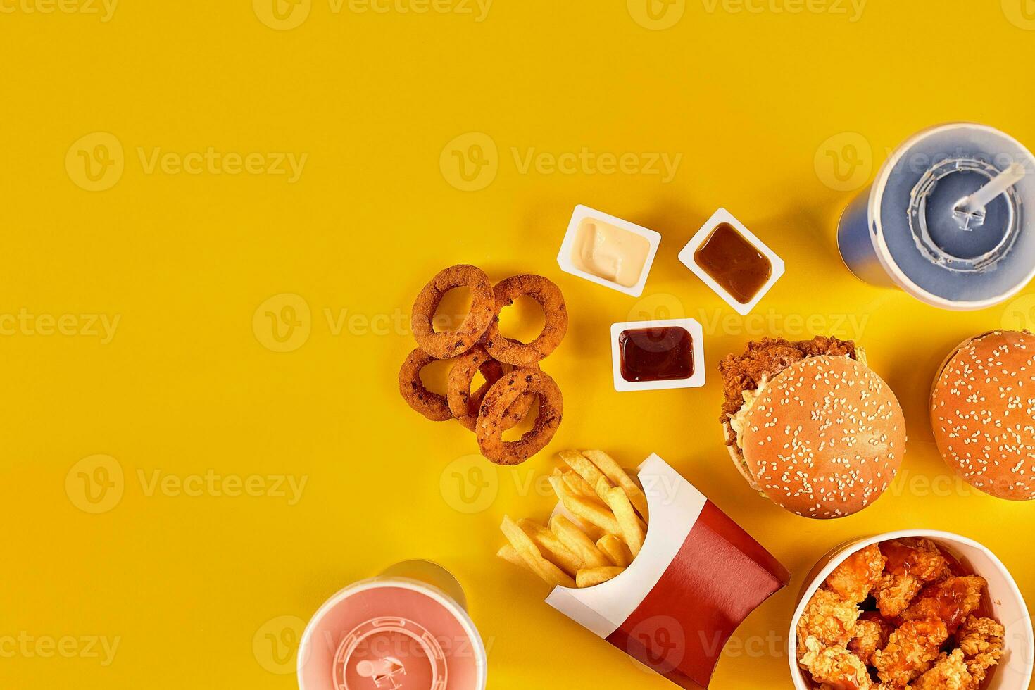 Fast food dish top view. French fries, hamburger, mayonnaise and ketchup sauces on yellow background. photo