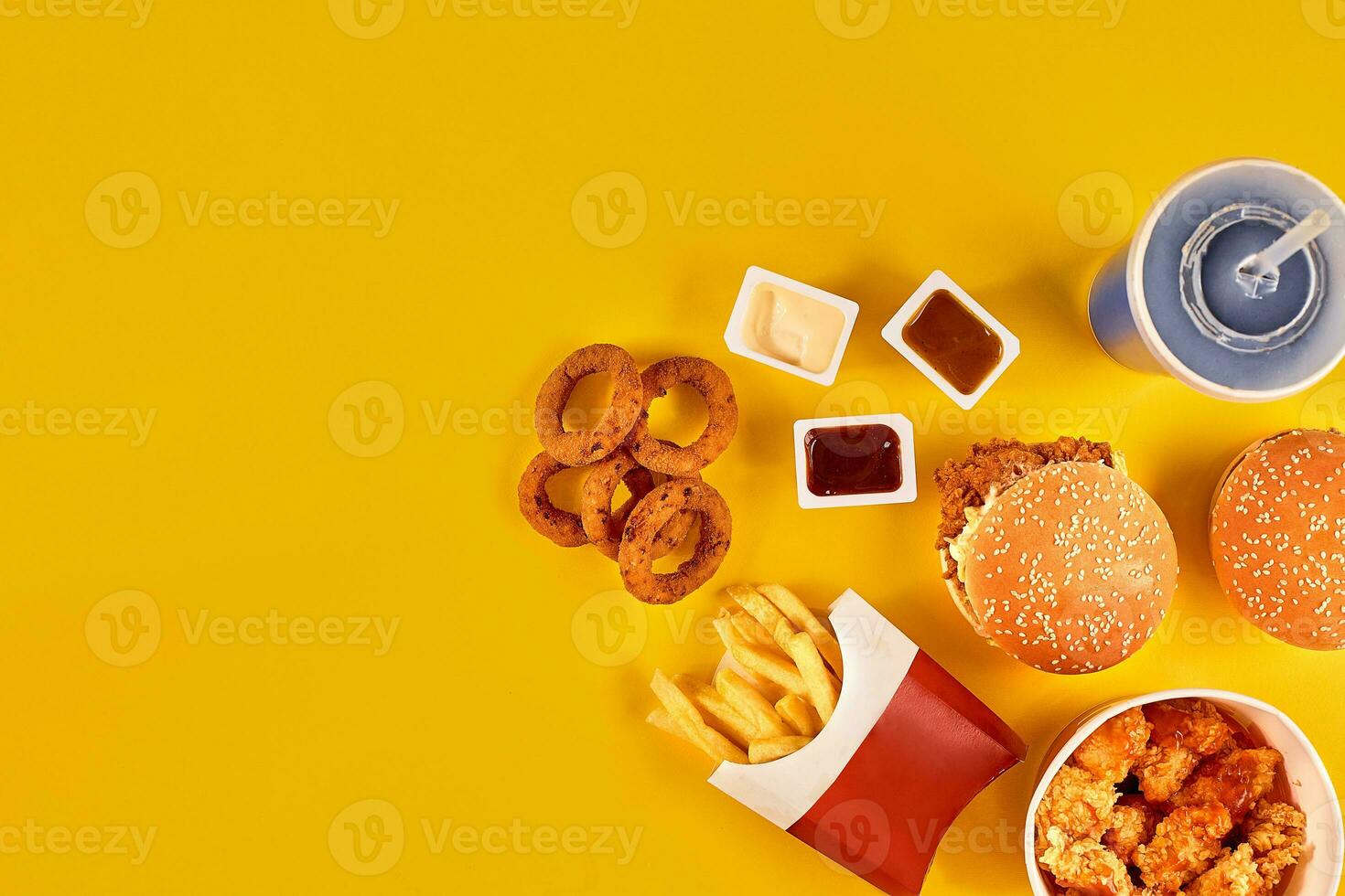 Fast food dish top view. French fries, hamburger, mayonnaise and ketchup sauces on yellow background. photo