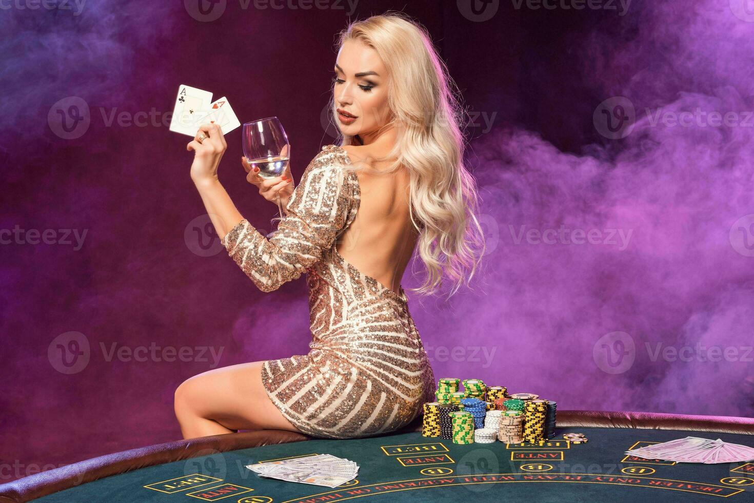 Blonde woman with a perfect hairstyle and bright make-up is posing with playing cards in her hands. Casino, poker. photo