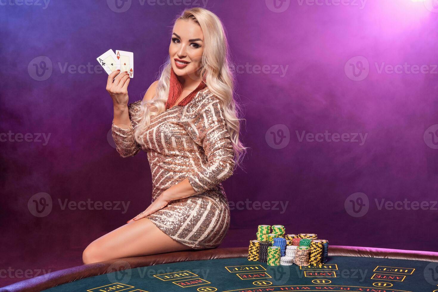 Blonde woman with a perfect hairstyle and bright make-up is posing with playing cards in her hands. Casino, poker. photo