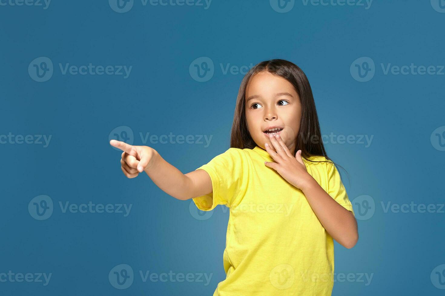 Cute girl shows finger on blue background photo