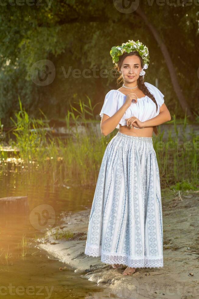 joven hermosa caucásico mujer en pie a el banco de río. tradicional campo imagen con niña a primer plano y Copiar espacio. foto