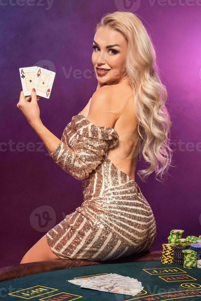 rubia mujer con un Perfecto peinado y brillante maquillaje es posando con jugando tarjetas en su manos. casino, póker. foto