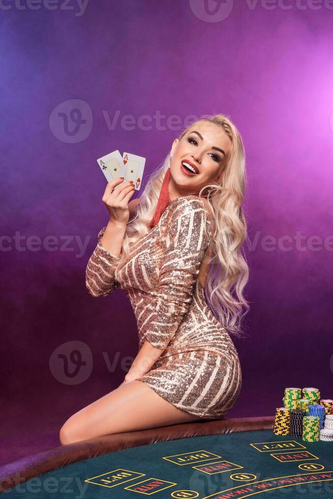 Blonde woman with a perfect hairstyle and bright make-up is posing with playing cards in her hands. Casino, poker. photo