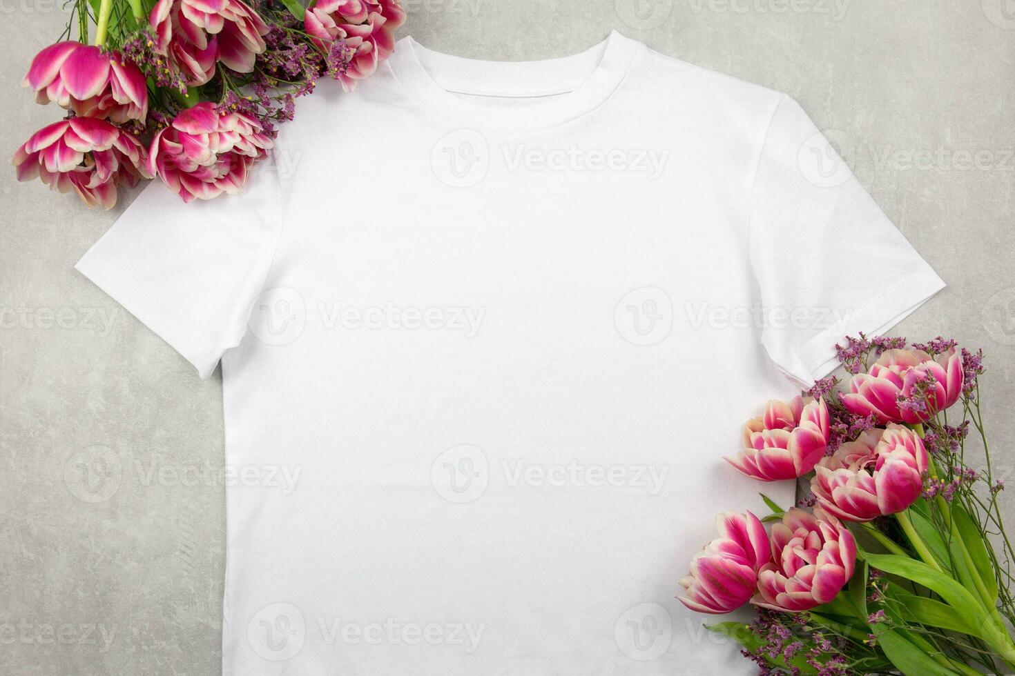 White womens cotton t-shirt mockup with pink tulips flowers on gray concrete background. Design t shirt template, print presentation mock up. Top view flat lay. photo