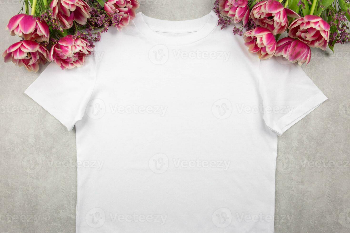 White womens cotton t-shirt mockup with pink tulips flowers on gray concrete background. Design t shirt template, print presentation mock up. Top view flat lay. photo