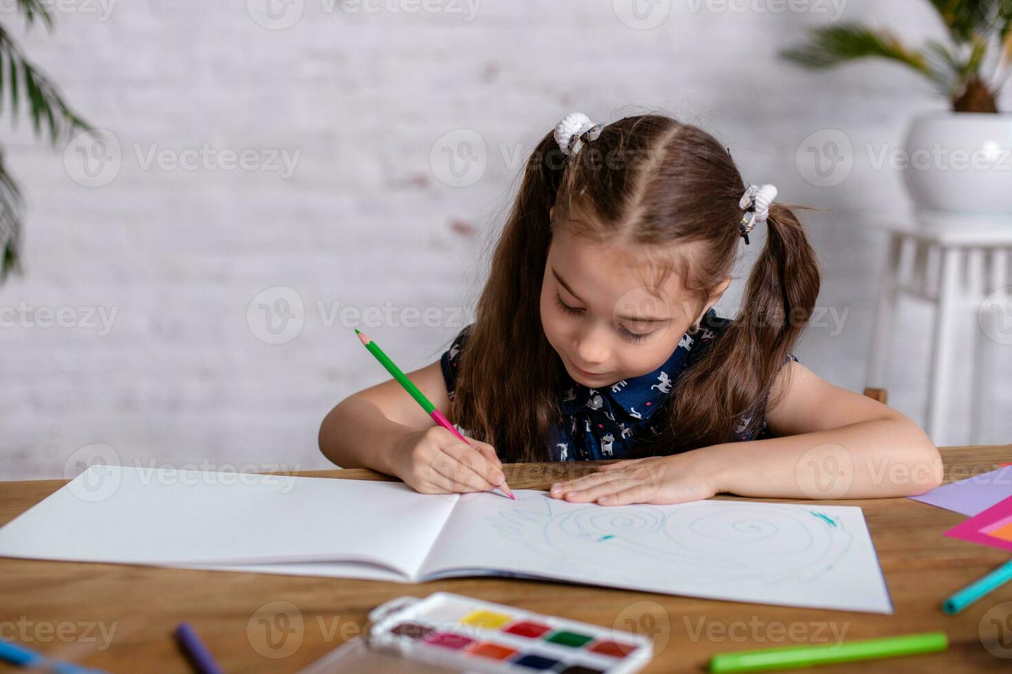 Inspired little girl at the table draw with crayons or do home work photo