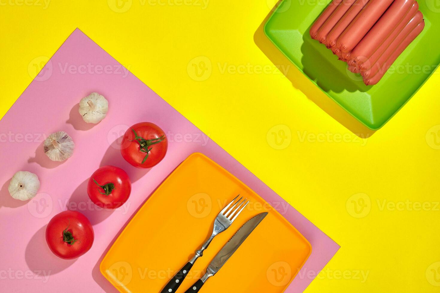 Stack of thin wiener sausages with tomatoes on plate on pink and yellow background photo