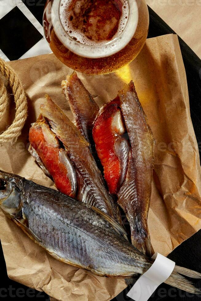 Whole and skinned salted air-dried roach with roe served on wrapping kraft paper with beer photo