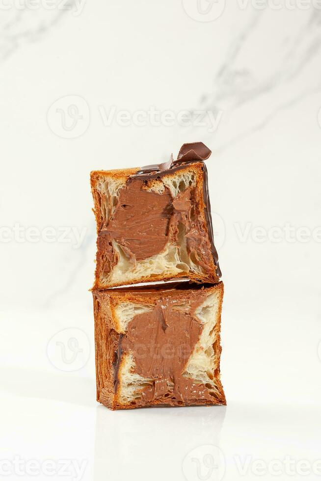 Two halves of cube shaped croissant with chocolate custard, ganache and chocolate chips photo
