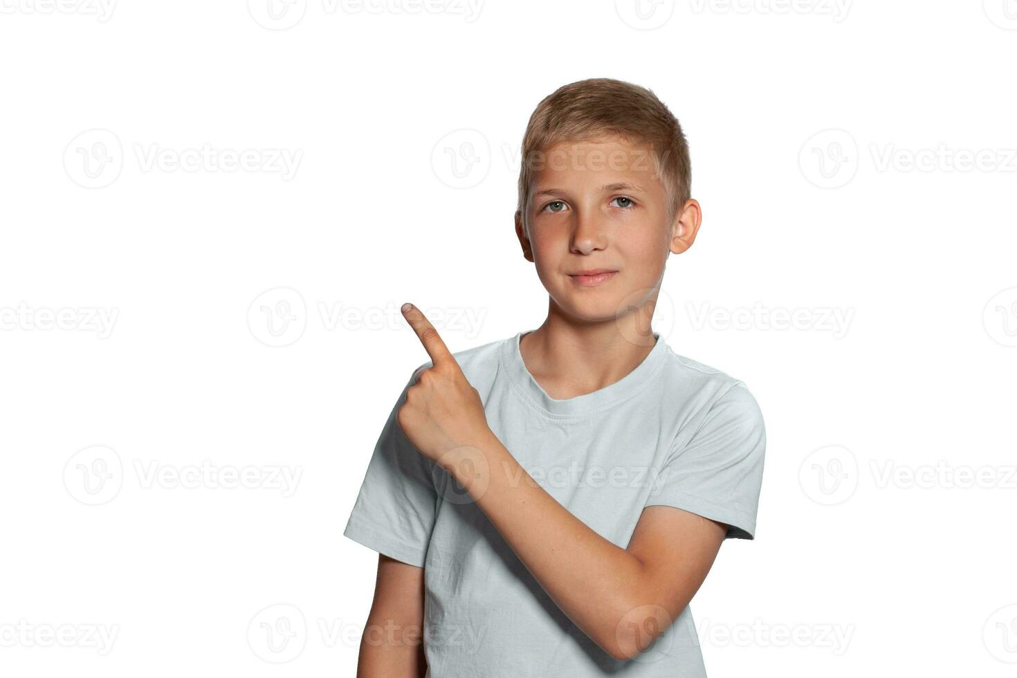 Close-up portrait of a blonde teenage boy in a white t-shirt posing isolated on white studio background. Concept of sincere emotions. photo