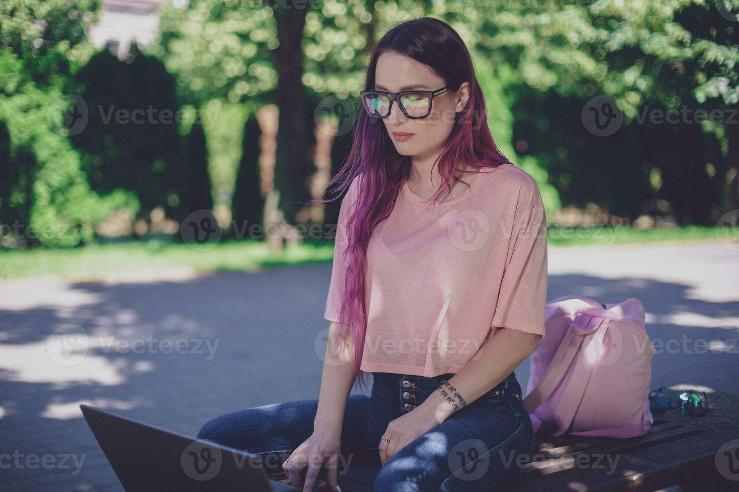 Young girl is studying in the spring park, sitting on the wooden photo