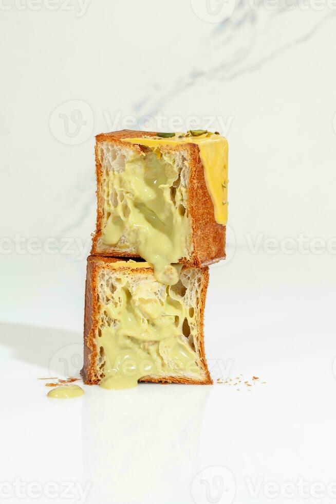 Sliced fluffy cube shaped croissant with pistachio custard cream sprinkled with nuts photo