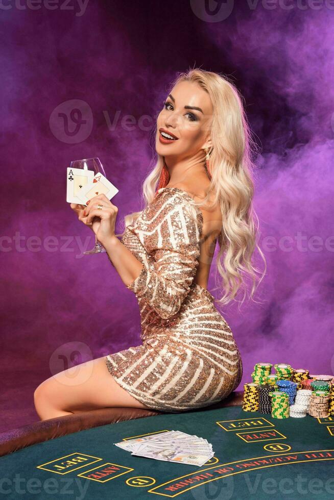 rubia mujer con un Perfecto peinado y brillante maquillaje es posando con jugando tarjetas en su manos. casino, póker. foto