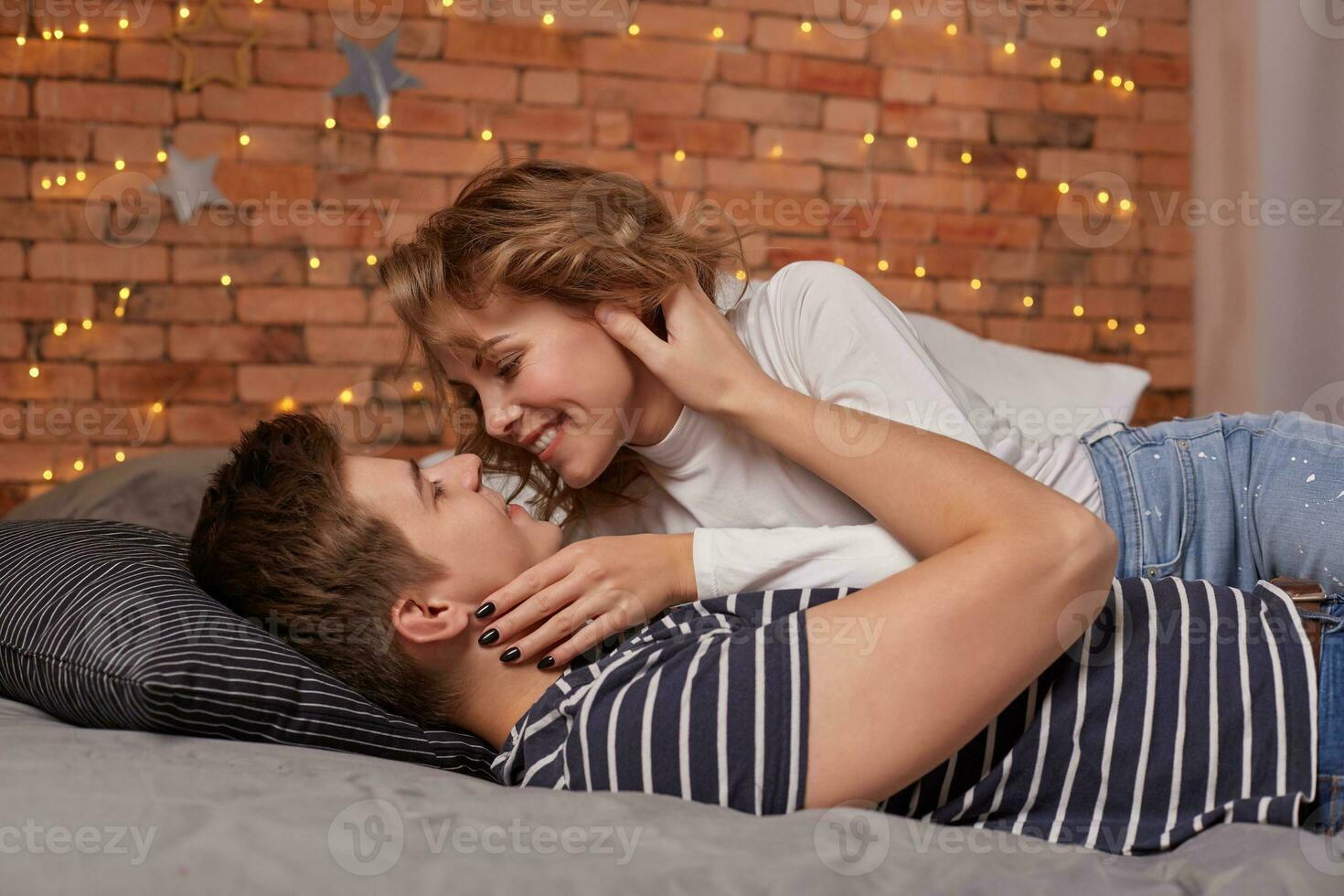 Caucasian young beautiful couple lie on bed and hugging each other photo