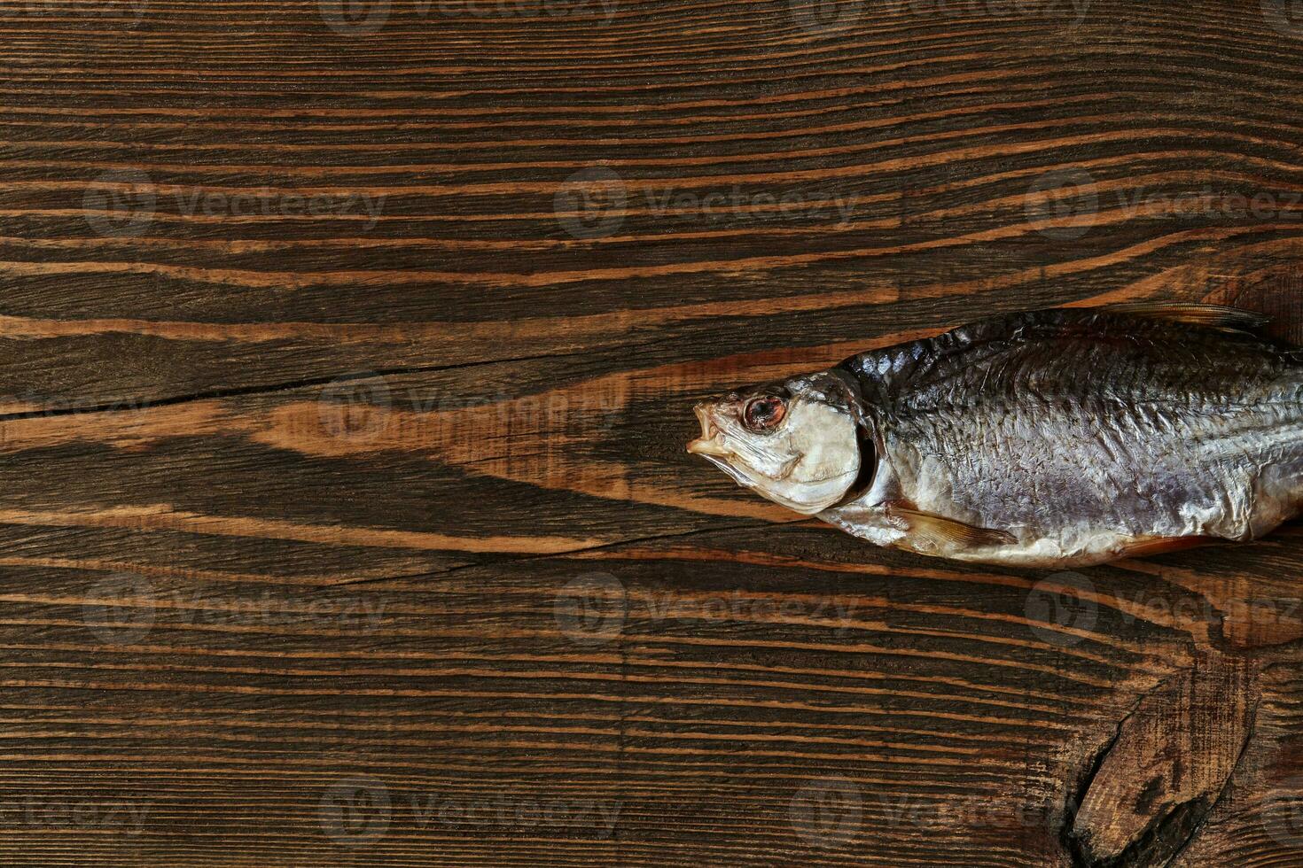 One dried or jerky salted roach, tasty clipfish on wooden background. Salty beer appetizer. Traditional way of preserving fish. Close up photo