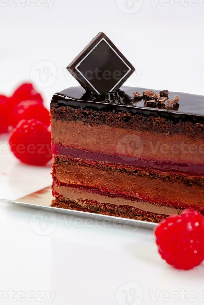 Slice of chocolate cake with airy mousse and raspberry jelly on white background photo