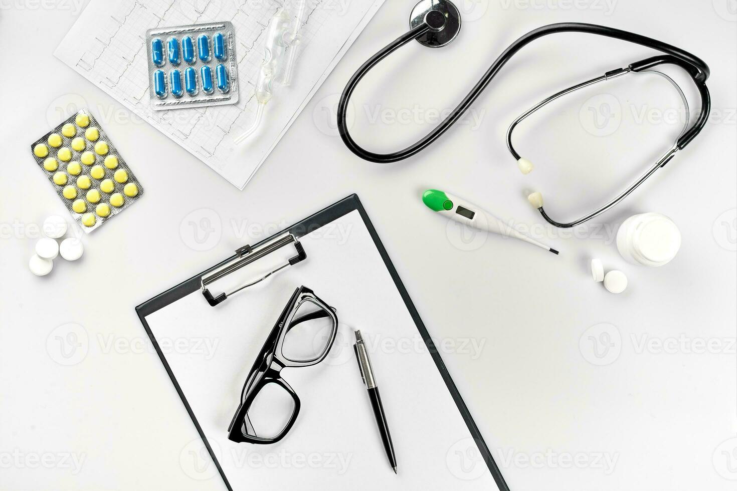 negocio conjunto para hospital pastillas, estetoscopio, médico equipo, Nota libro con bolígrafo y lentes en blanco antecedentes. moderno del doctor conjunto en el mesa. foto