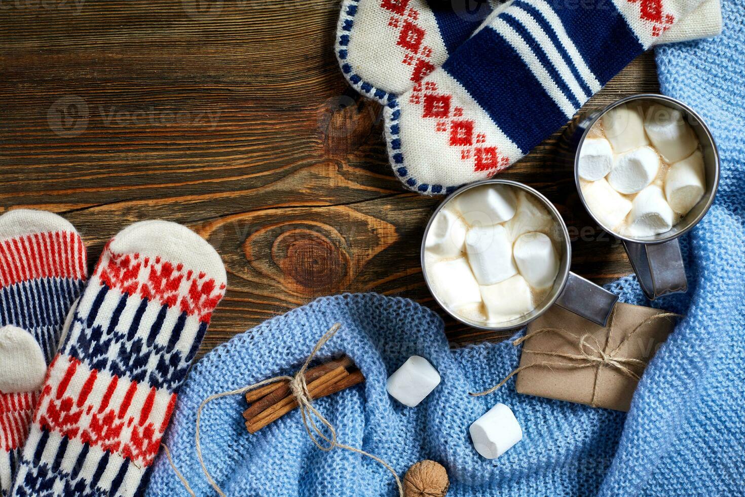 Two cups of hot cocoa or chocolate with marshmallow, mittens, christmas decor and fir tree on wooden rustic background from above. photo