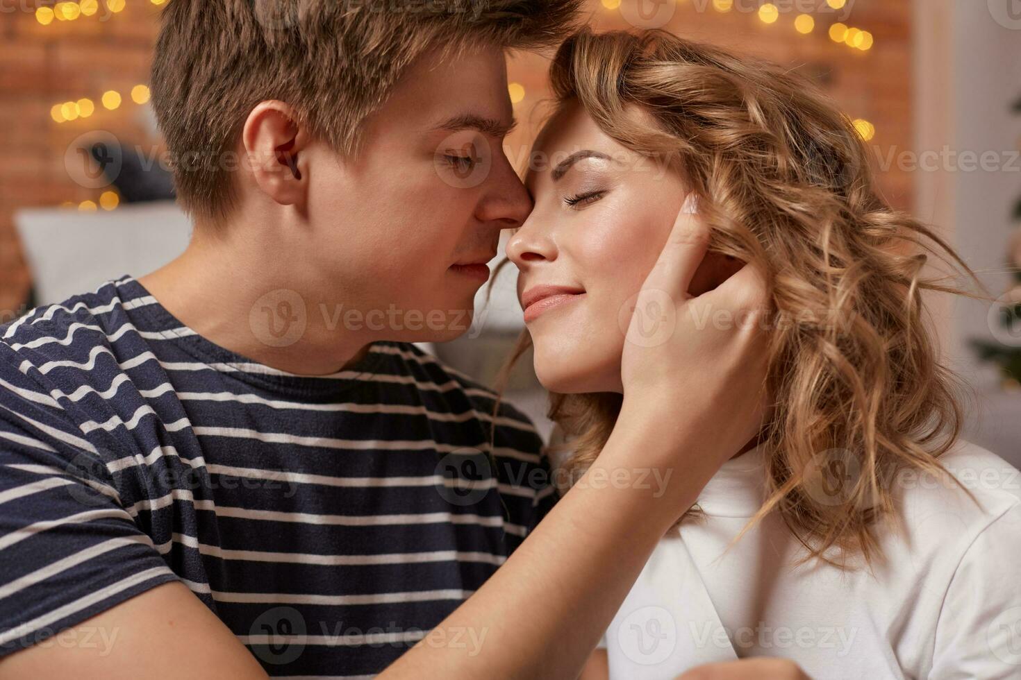Close up portrait of a beautiful couple sitting on the floor embracing and looking to each other photo
