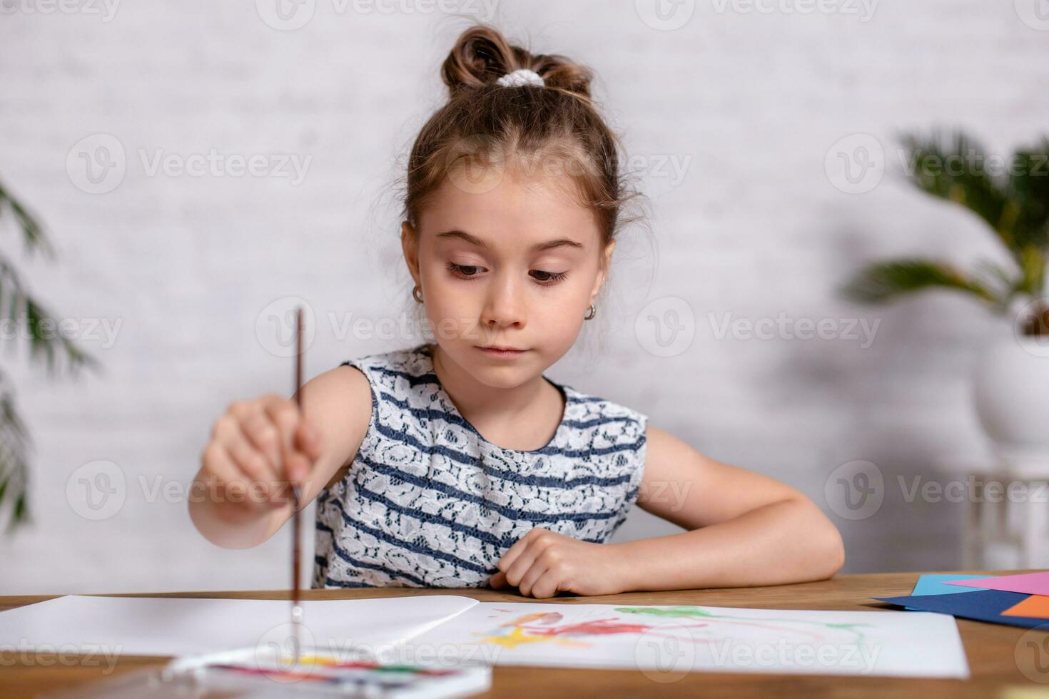 Inspired little girl at the table draw with paints photo