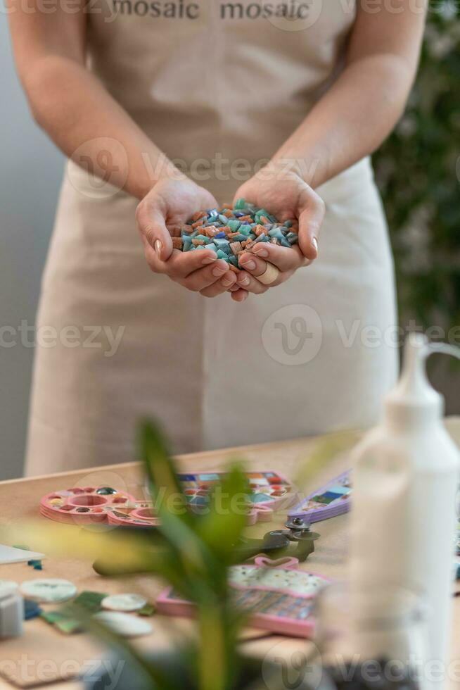 Workplace of the mosaic master women's hands holding mosaic details in the process of making a mosaic photo