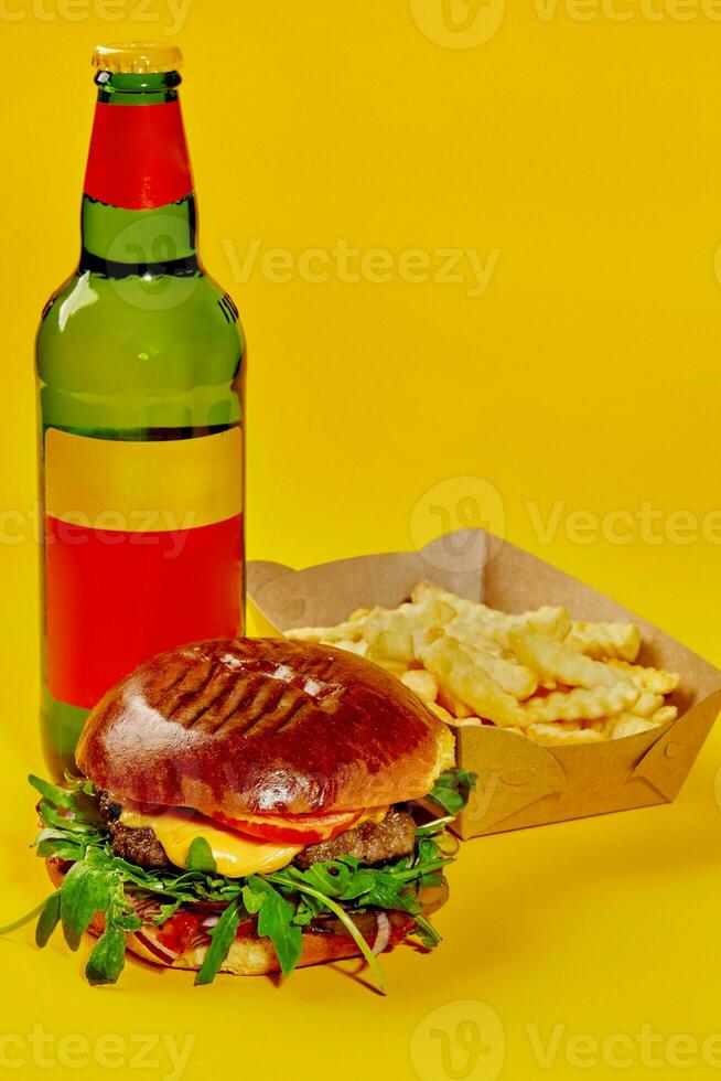 Cheeseburger with veal patty served with fries and drink in bottle on yellow background photo