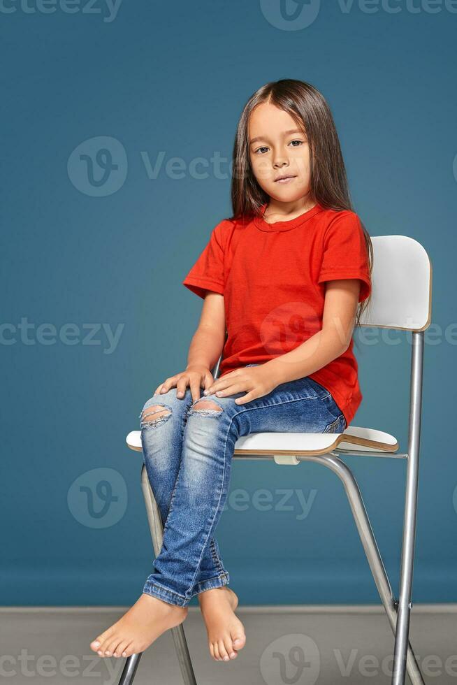 little girl wearing red t-short and posing on chair photo