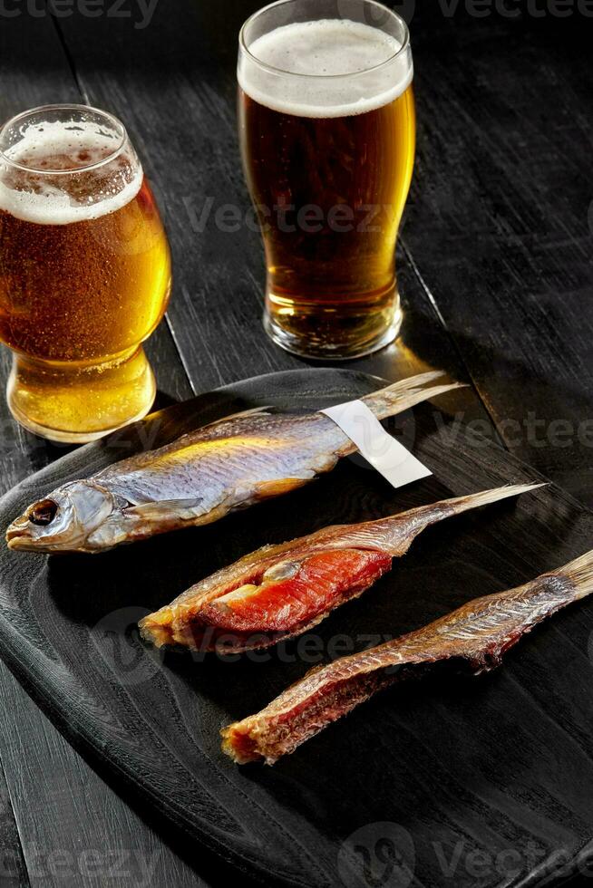 Whole salted air-dried roach fish and two peeled fish with caviar served with beer photo