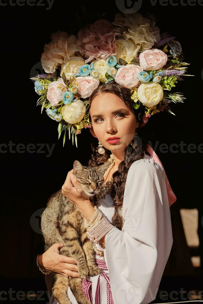 Brunette girl in a white ukrainian authentic national costume and a wreath of flowers is posing for the camera. Close-up. photo