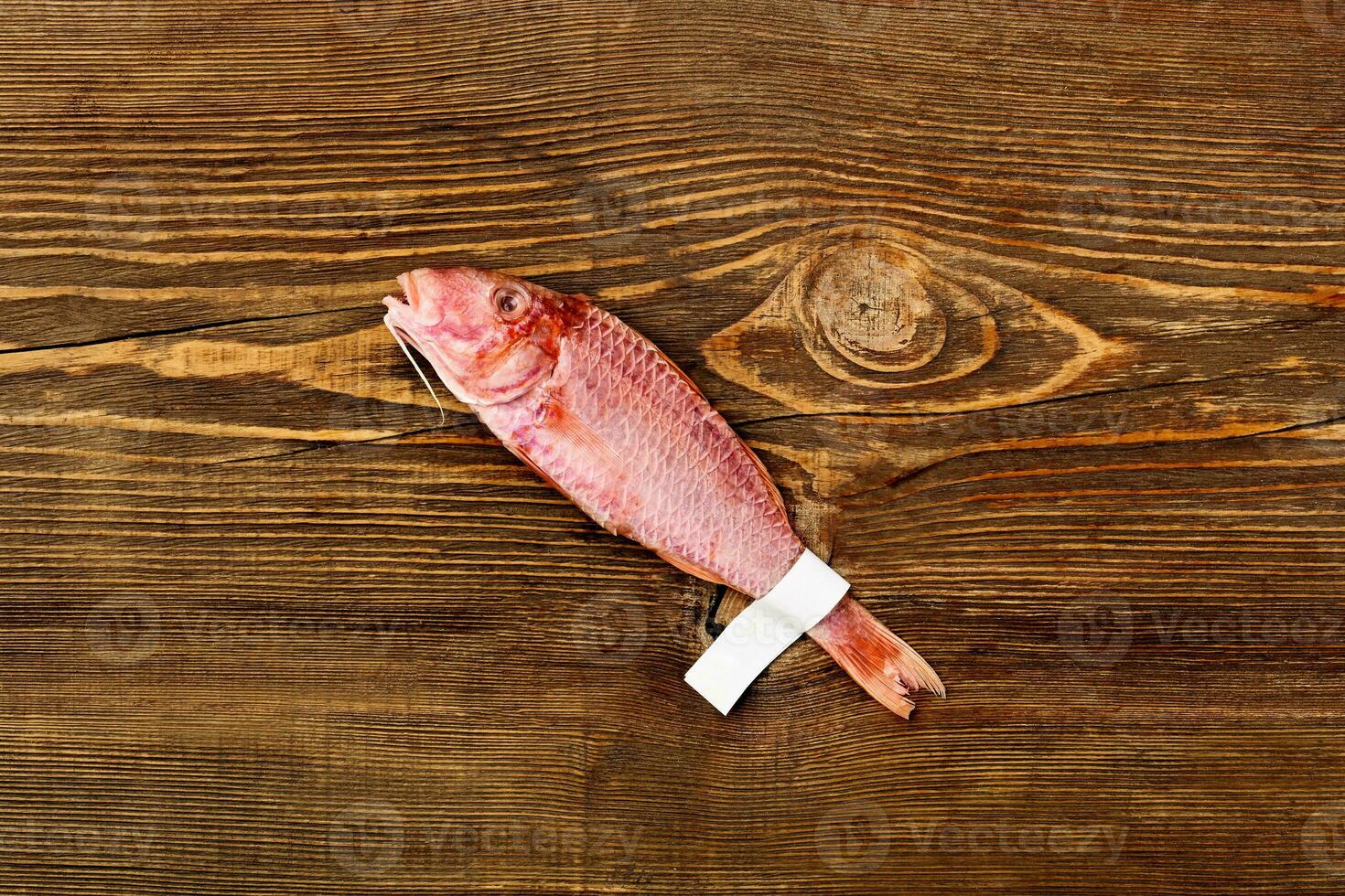 Salted sun-dried red mullet with label on tail on wooden table photo