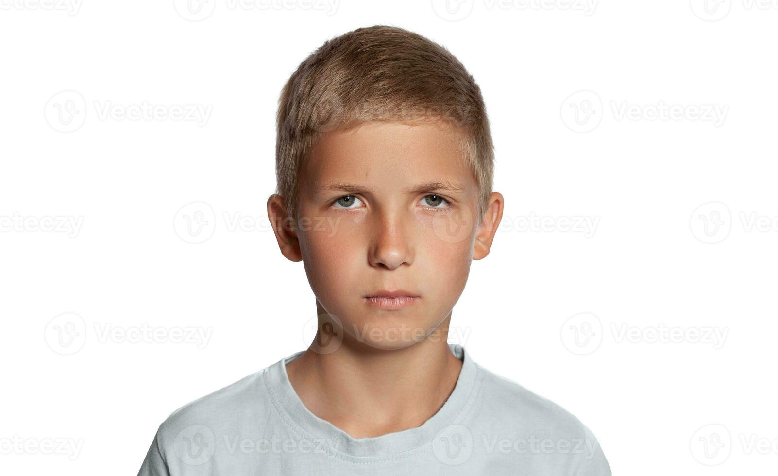 Close-up portrait of a blonde teenage boy in a white t-shirt posing isolated on white studio background. Concept of sincere emotions. photo