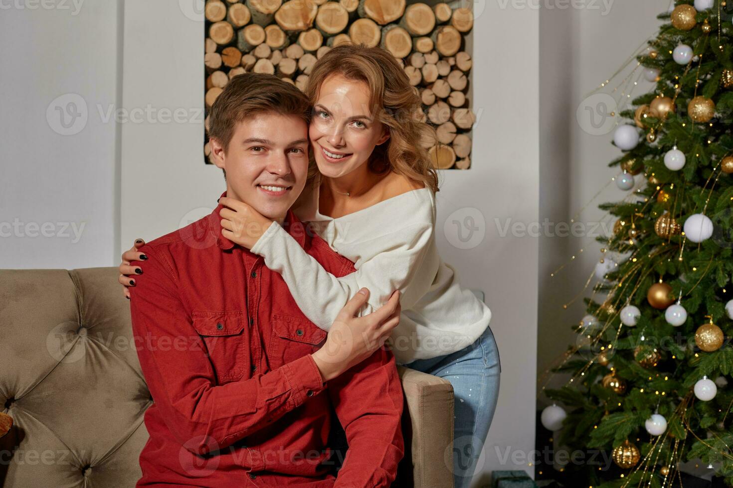 Happy young lovely couple on living room sitting on the couch near christmass tree photo