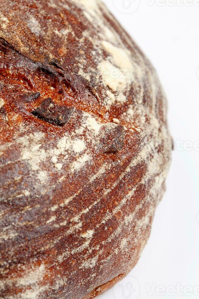 Closeup of browned crust of wheat loaf of bread on white background photo